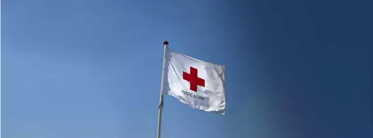 Dansk r&oslash;de kors flag med bl&aring; himmel i baggrunden